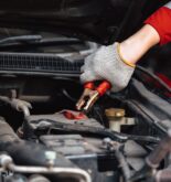 closeup mechanic male hand holding battery clamps grip for charging car battery in auto repair works
