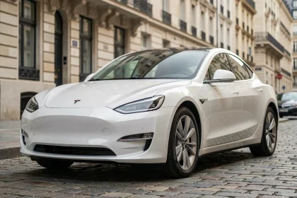 Berline électrique de marque asiatique garée dans une rue pavée européenne, vue en angle 3/4 avant mettant en valeur son design aérodynamique