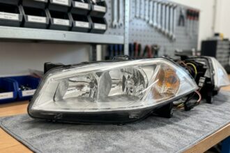 Phare avant Renault Mégane 2 posé sur un établi d'atelier automobile, vue détaillée de l'optique et du clignotant